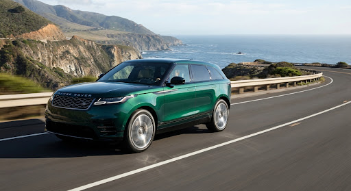 A dark green SUV on a scenic coastal highway.